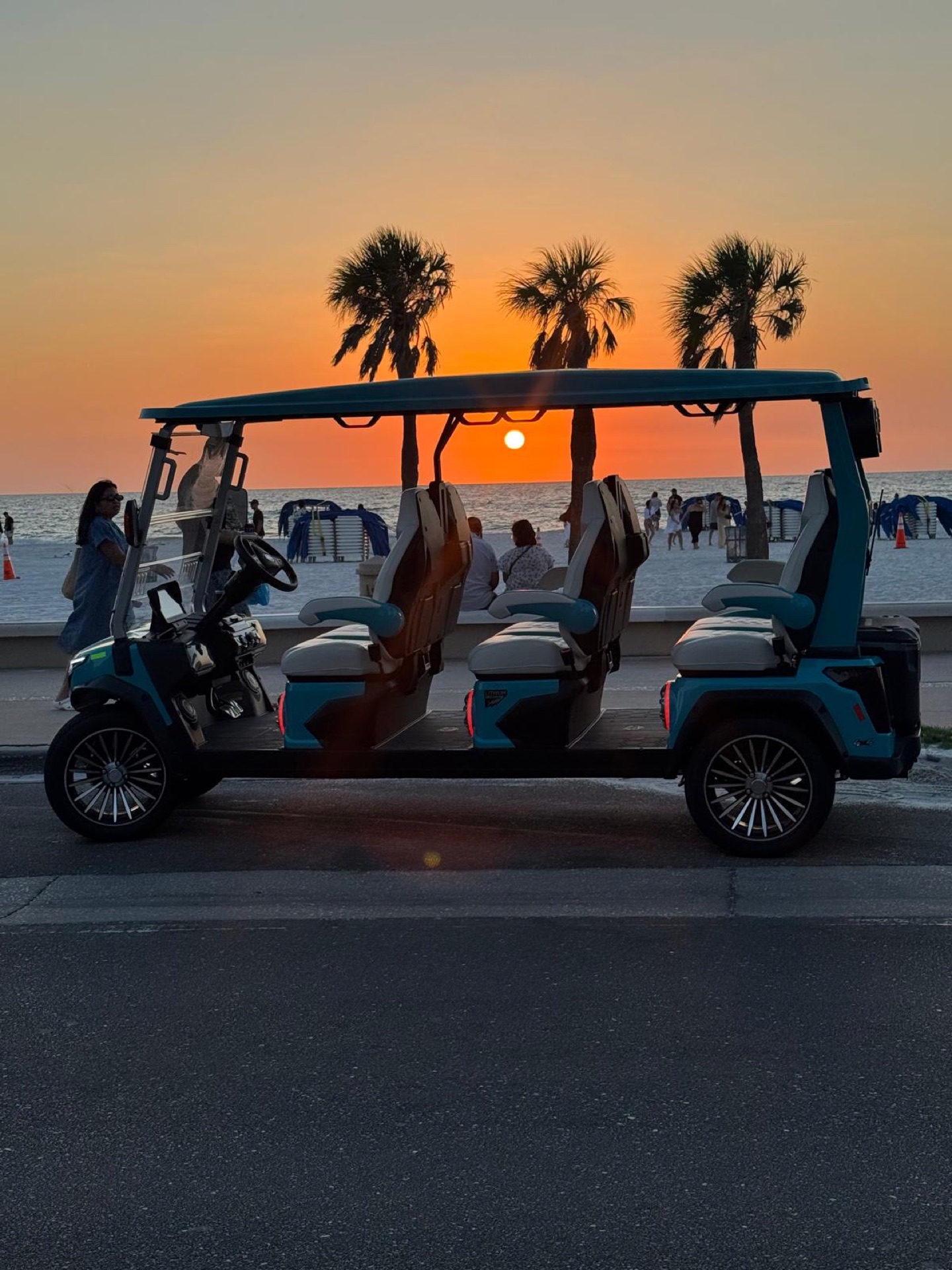 Sandy Golf Cart Rentals 6-passenger golf cart silhouetted against a Clearwater Beach sunset
