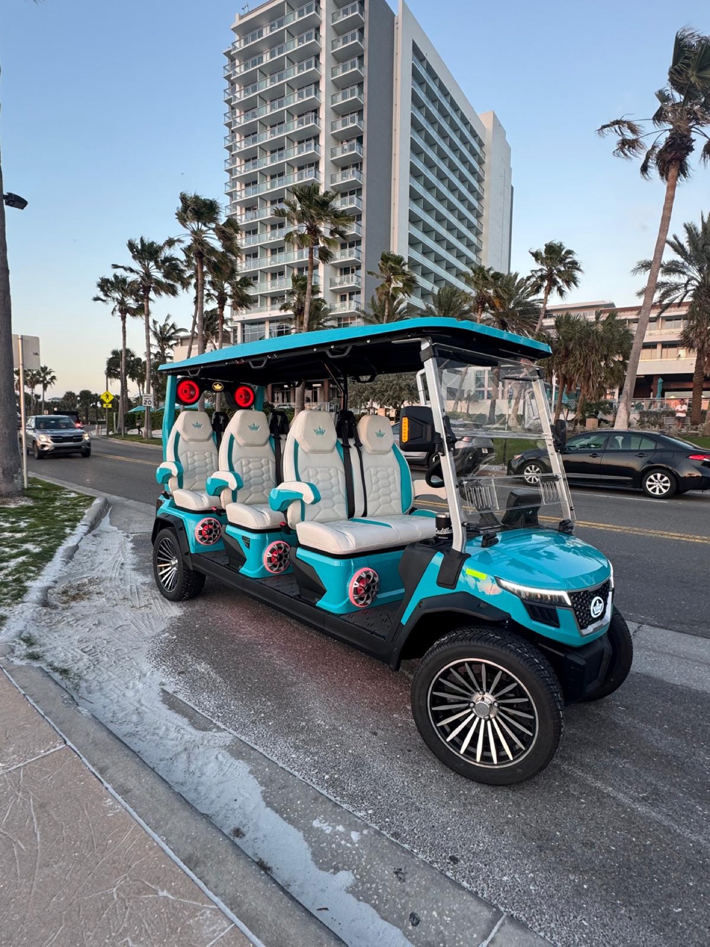 Sandy Golf Cart Rentals 4-passenger teal cart parked by the beachfront hotel in Clearwater Beach